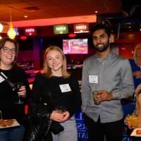 Four alumni with food and drinks at the event together.